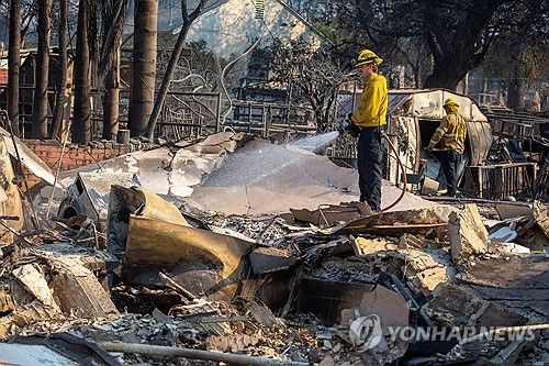 10일(현지시간) LA 이튼 산불 지역 잔불 진화 중인 소방관들