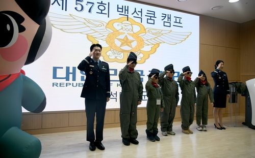 캠프에 참가한 어린이들이 공군 조종복을 입고 경례하는 모습