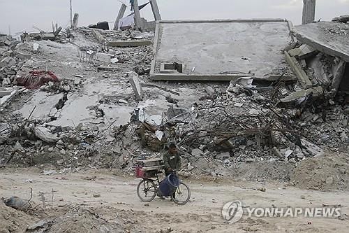 건물 잔해 옆 걷는 가자지구 주민