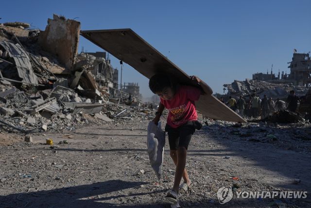 11일 가자시티에서 나무판을 들고 가는 팔레스타인 소년