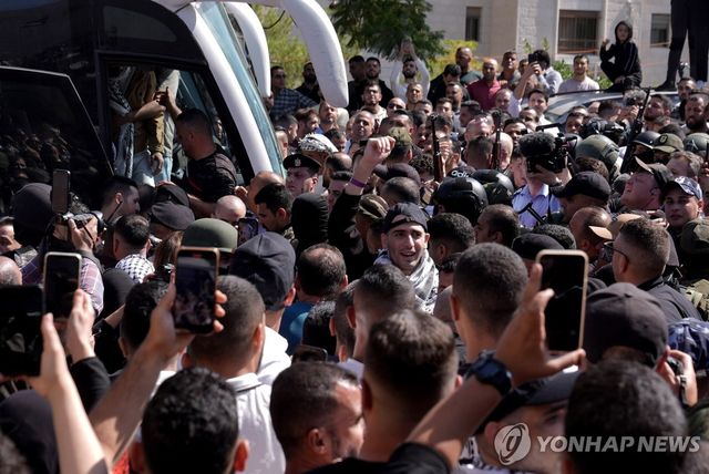 13일(현지시간) 가자지구에서 이스라엘군에 구금됐다 풀려난 팔레스타인 수감자들을 태운 버스가 인파에 둘러싸여 있다. 
