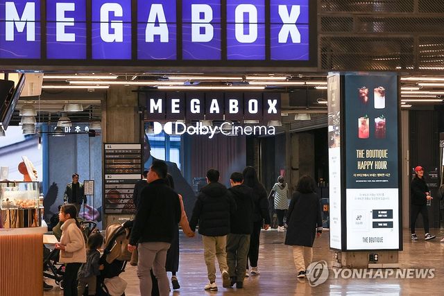 영화관에서 상영작 예고 영상 살펴보는 시민들