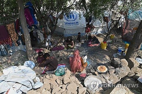 임시 천막 앞에서 빵 굽는 아프간 여성