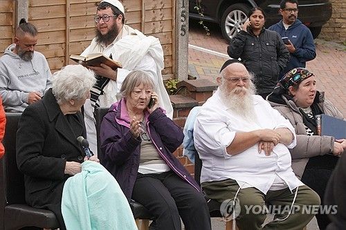 테러가 발생한 회당 앞에 머물고 있는 신도들 