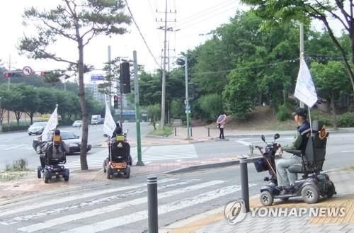 의료용 스쿠터를 타고 가는 사람들