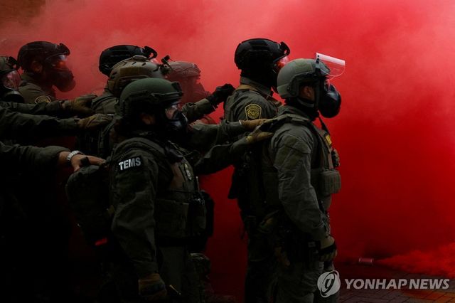 4일(현지시간) 미국 오리건주 포틀랜드의 이민세관단속국(ICE) 본부 앞에서 벌어진 시위에 맞서 연방요원들이 연막을 피우고 서 있다. [로이터=연합뉴스. 재판매 및 DB 금지]