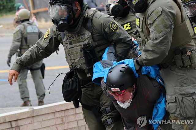 미국 연방요원들이 4일(현지시간) 오리건주 포틀랜드의 이민세관단속국(ICE) 본부 앞에서 시위 참가자를 체포하고 있다. [로이터=연합뉴스. 재판매 및 DB 금지]