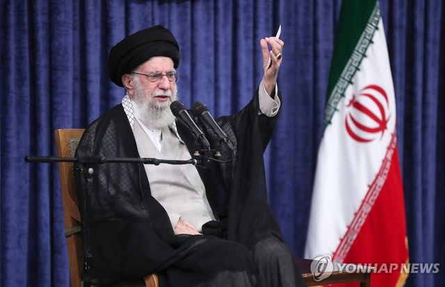 이란 국기 곁에 앉은 아야톨라 세예드 알리 하메네이 이란 최고지도자