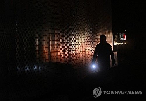 지난 12일 손전등을 켜고 정전된 키이우 시내를 걷는 남성