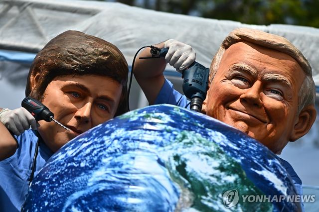 20일(현지시간) 미국 대통령(오른쪽)과 아르헨티나 대통령 가면 쓰고 퍼포먼스하는 세계 구호활동 운동가들