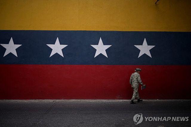 24일(현지시간) 베네수엘라 국기 벽화 지나가는 민병대원