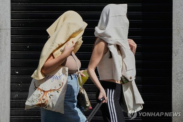 뜨거운 햇볕 가리는 스페인 거리의 여성들