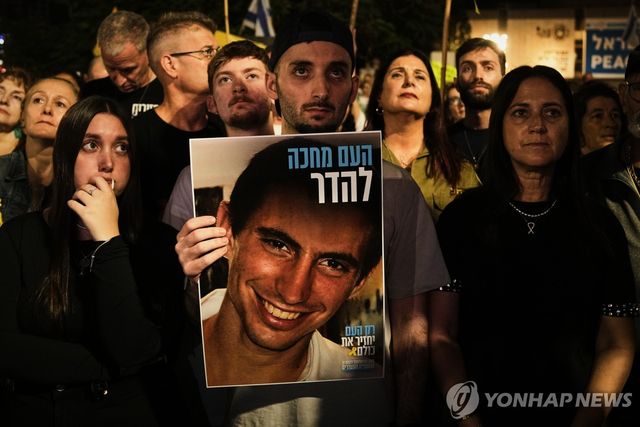 하마스가 11년여 만에 시신을 송환한 하다르 골딘 중위 사진을 든 석방된 이스라엘 인질