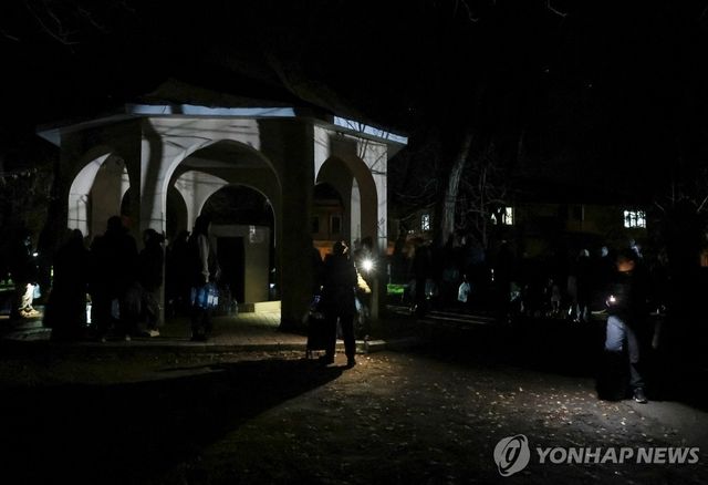 13일(현지시간) 러시아 공습 후 우크라이나 남부 도시 모습. 주민들이 어둠 속에서 식수를 받기 위해 줄을 서 있다.