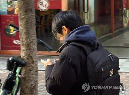 휴대폰을 보며 걸어가는 청소년