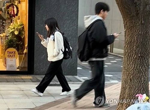 휴대폰 보며 걸어가는 청소년