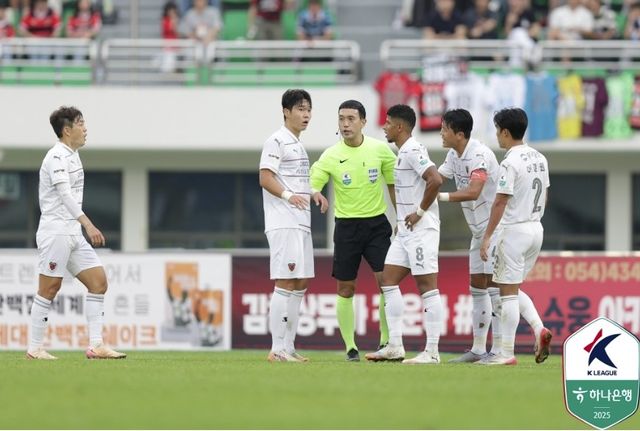 포항 선수단 사이의 김우성 주심