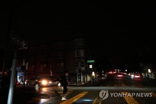 정전으로 어둠에 빠진 샌프란시스코 시내에서 손전등에 의지해 길을 건너는 시민 [AP 연합뉴스. 재판매 및 DB 금지]