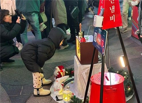 크리스마스이브인 24일 오후 9시 27분께 서울 중구 명동 거리에서 어린 아이가 구세군 냄비 앞에 놓인 장식물을 들여다보는 모습. [촬영 조윤희 수습기자]