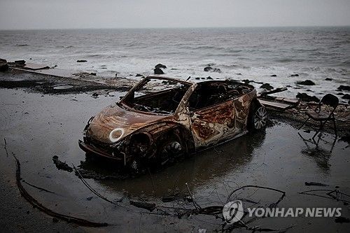 산불에 탄 차량이 폭우로 바닷가에 떠내려온 모습 