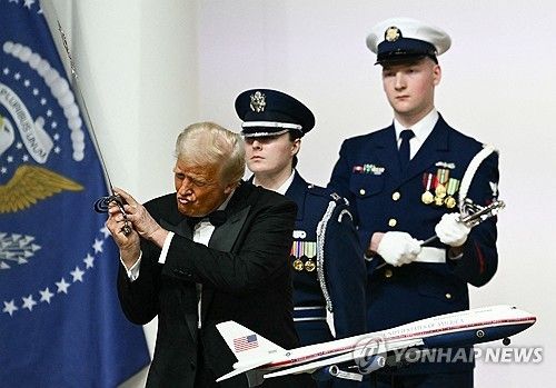 지난달 20일(현지시간) 백악관에서 열린 취임식에서 도널드 트럼프 미국 대통령이 기념 케이크 위에 놓인 에어포스원 모형 앞에서 포즈를 취해 보이고 있다. [AFP=연합뉴스 자료사진]