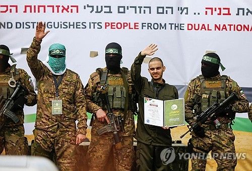 하마스의 강요로 팔레스타인 군중을 향해 손을 흔드는 이스라엘 인질 