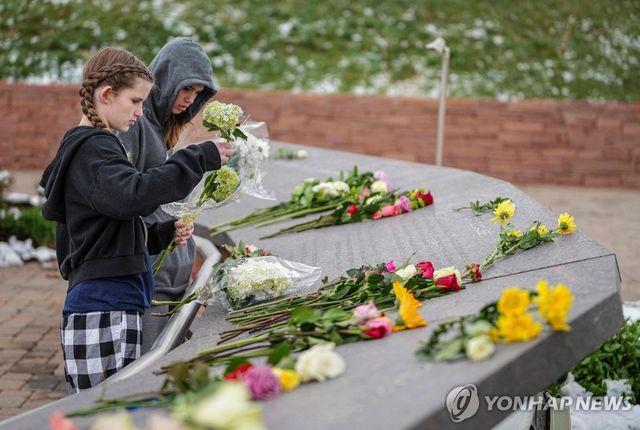 컬럼바인 고등학교 학생들이 지난해 4월 25주기에 희생자 추모비에 꽃을 놓는 모습