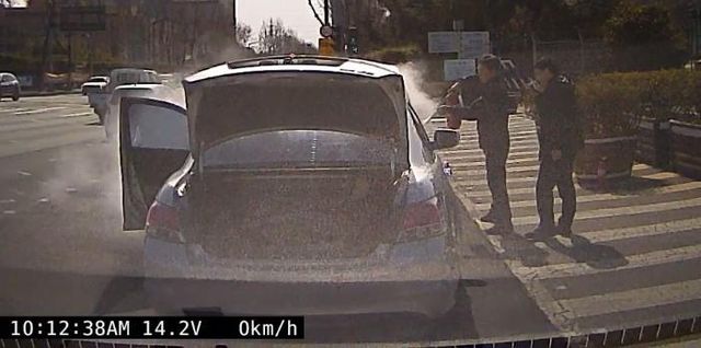 차량에 난 불 진화 중인 경찰관