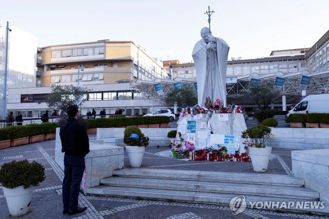 요한 바오로 2세 동상 앞에서 프란치스코 교황 쾌유 기원하는 한 남성