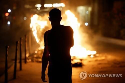 프랑스 파리에서 불타는 컨테이너를 바라보고 있는 행인