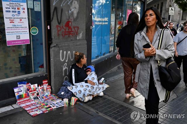 아르헨티나 거리에서 아기를 안고 물건 파는 여인