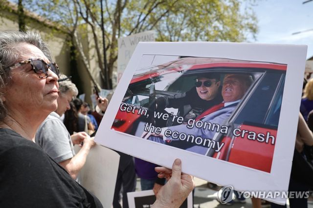 미 캘리포니아의 한 시위자가 트럼프 대통령과 머스크를 비판하는 내용을 담은 피켓을 들고 있다. 