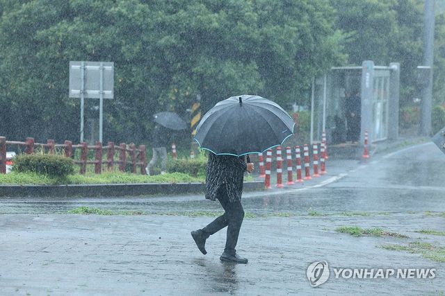 제주 서귀포시 남원읍 하례리 입구에서 우산을 쓴 시민들이 길을 가고 있다. [연합뉴스 자료사진]