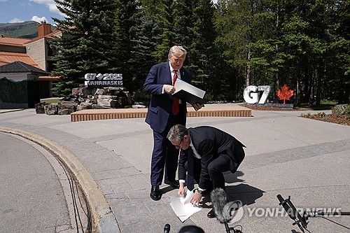 무역협정문 떨어뜨린 트럼프 미국 대통령과 이를 줍는 스타머 영국 총리