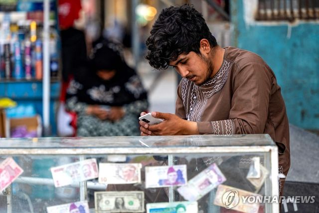 아프간 수도 카불서 휴대전화를 보는 환전상