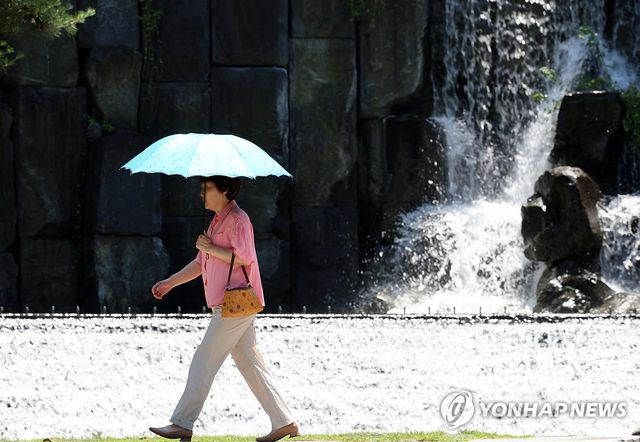 내리쬐는 햇볕에 양산 쓴 시민