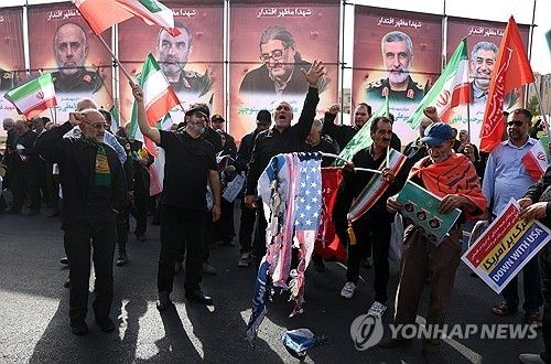 28일 이스라엘의 공습으로 숨진 핵 과학자 등의 장례식에서 이란 주민들이 이스라엘과 이란의 국기를 태우고 있다. [EPA 연합뉴스. 재판매 및 DB 금지]