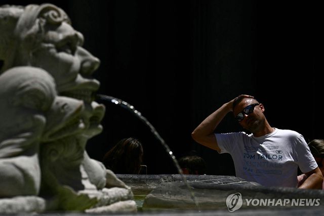 이탈리아 로마의 한 분수대에서 물로 머리를 식히는 관광객 