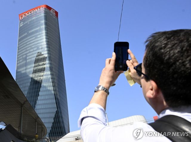 주저앉은 제네랄리 간판을 휴대전화로 촬영하는 한 남성