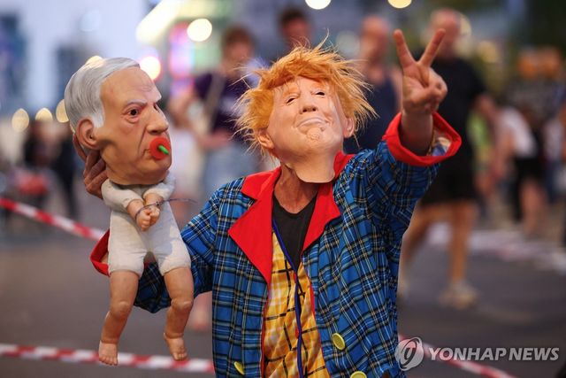 지난 28일 이스라엘 텔아비브에서 열린 시위에서 한 참가자가 탈과 인형으로 도널드 트럼프 미국 대통령과 베냐민 네타냐후 이스라엘 총리의 관계를 비판하고 있다. [로이터 연합뉴스. 재판매 및 DB 금지]