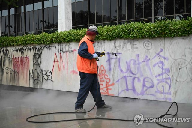 9일 오전 LA 도심에서 시위대가 남긴 낙서를 지우는 청소 노동자