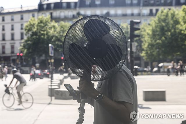 선풍기를 든 채 파리 시내를 걷는 남성