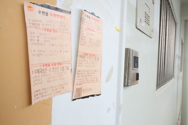 모자 집 현관문에 붙어 있는 등기 도착 안내서