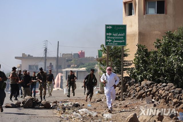 18일(현지시간) 베두인족 전투원들이 시리아 남부 스웨이다 지역 한 마을을 통과하고 있다. 