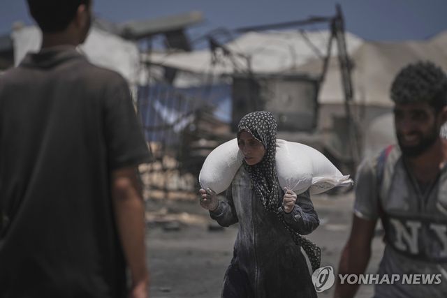 22일(현지시간) 가자시티에 도착한 인도주의 구호품 호송대에서 내린 밀가루를 나르는 팔레스타인 주민