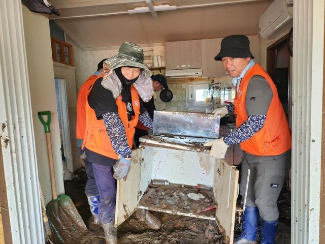 가평 수해 주택에서 자원봉사자들이 젖은 가구를 옮기는 모습