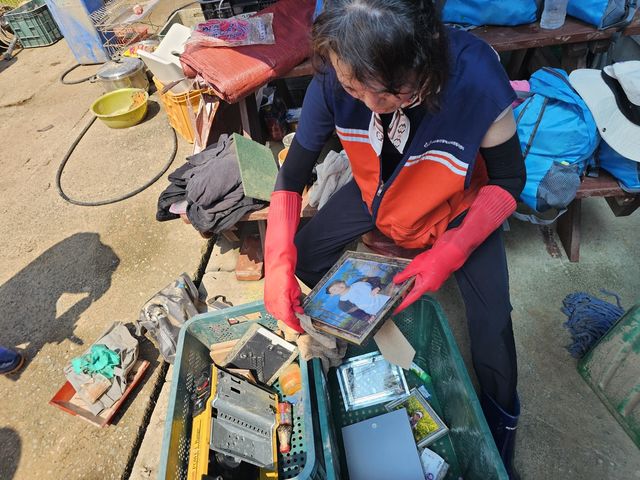 경남 산청의 수해피해 가구의 사진액자를 정리하는 자원봉사자