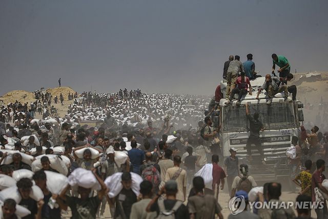 27일(현지시간) 가자지구 북부 식량 배급소 근처에서 밀가루 자루를 들고 가는 팔레스타인 주민들.[EPA=연합뉴스. 재판매 및 DB 금지]