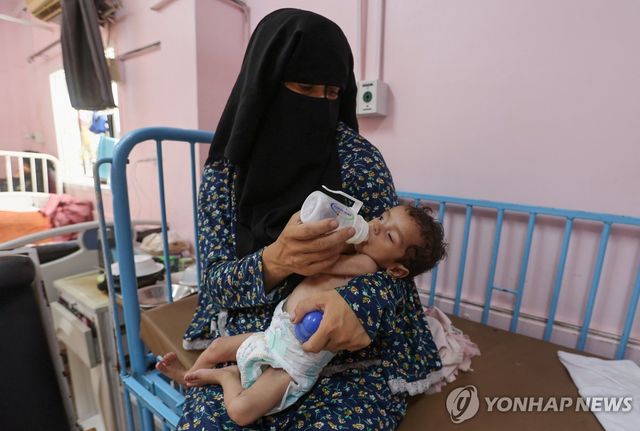 지난 27일(현지시간) 가자지구 남부 칸유니스 나세르 병원에서 팔레스타인 여성이 영양실조를 앓는 딸에게 분유를 먹이고 있다.[로이터=연합뉴스. 재판매 및 DB 금지]