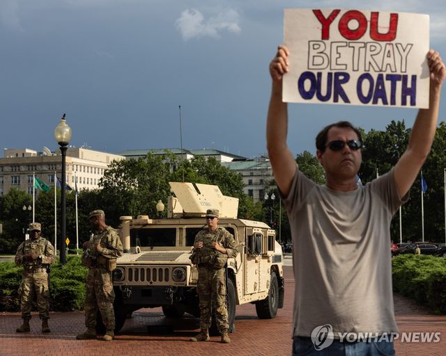 워싱턴DC에 배치된 주방위군 앞에서 시위를 하는 시민